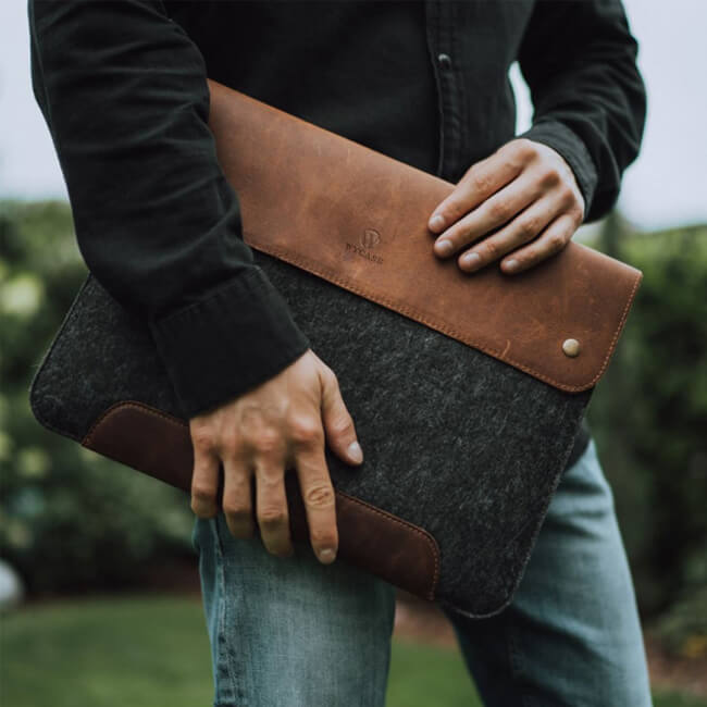 Person carrying a brown leather and gray felt laptop sleeve