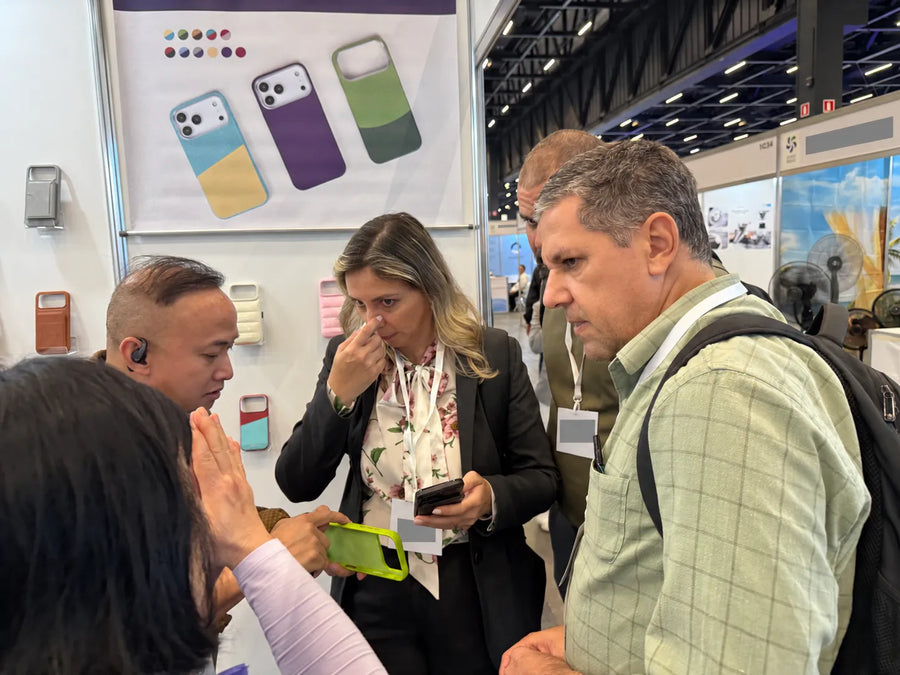 Visitors discussing a phone case sample with the team at the São Paulo trade show.