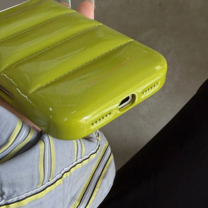Bottom opening and stitched puffer-style surface of the mustard-green case.
