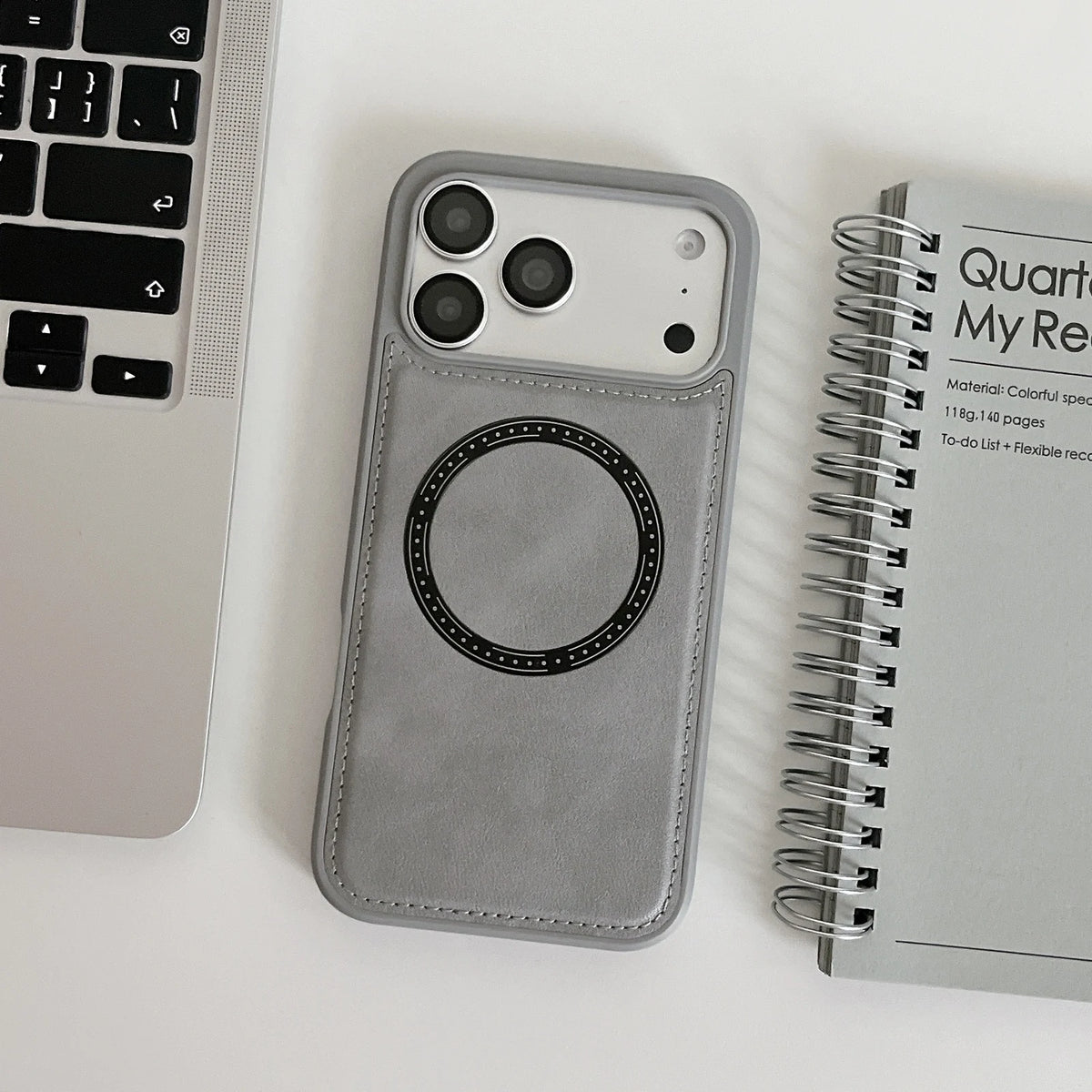 Gray stitched imitation leather ring phone case, shown beside computer and notebook props; props not included