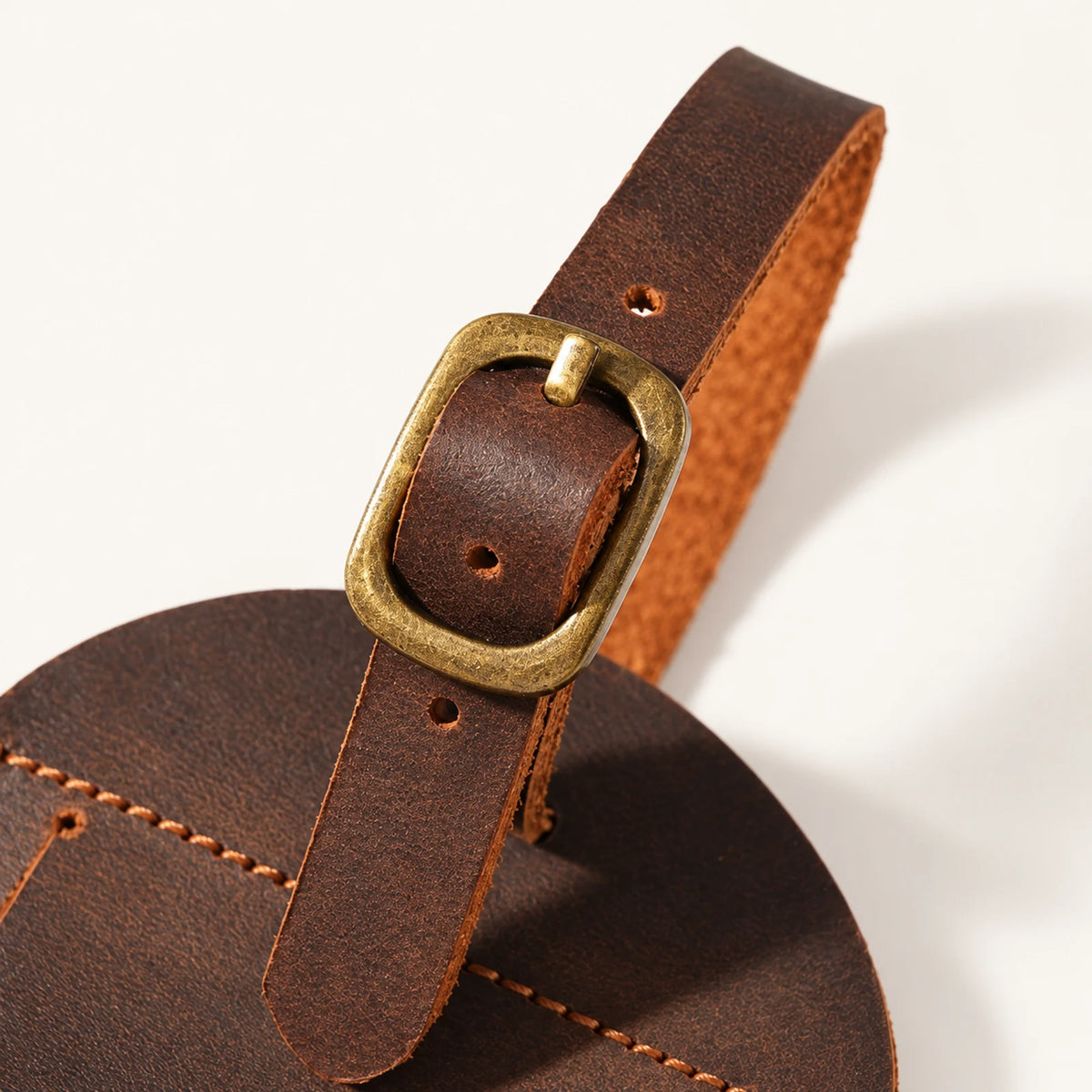Antique-brass-tone pin buckle detail on the arched luggage tag detachable leather strap