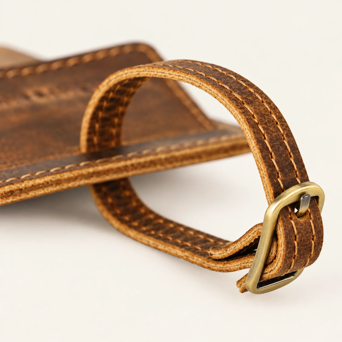 Close-up of stitched leather buckle strap on the rectangular cowhide luggage tag