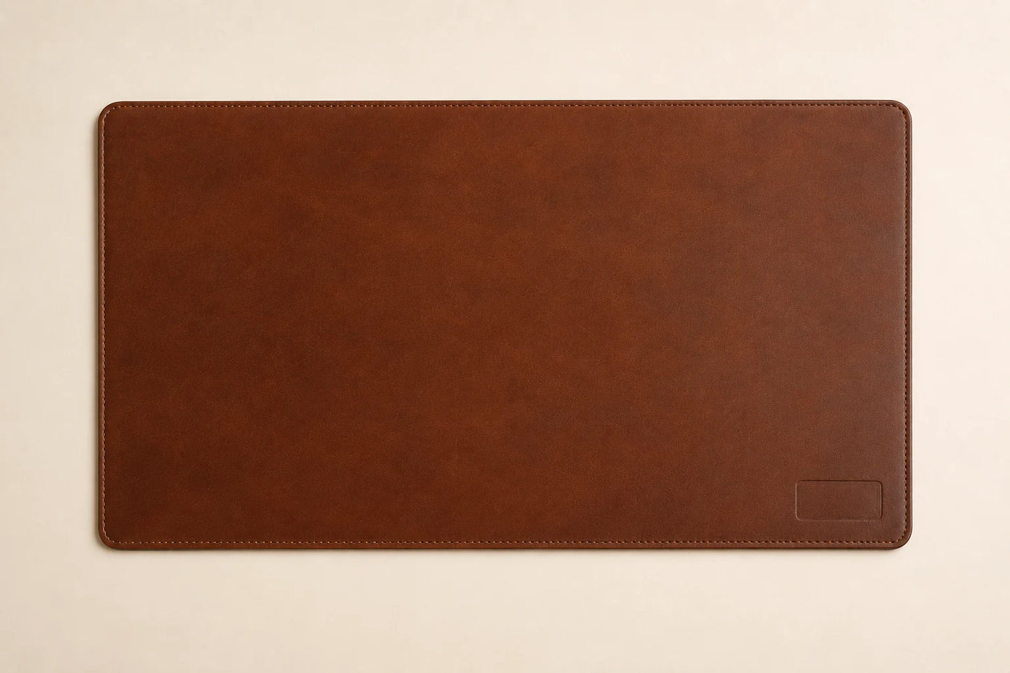 Top-down view of custom brown leather desk mat with stitched border and rounded corners