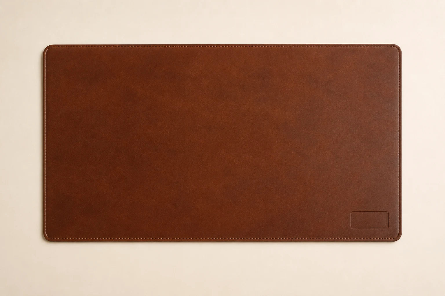 Top-down view of custom brown leather desk mat with stitched border and rounded corners