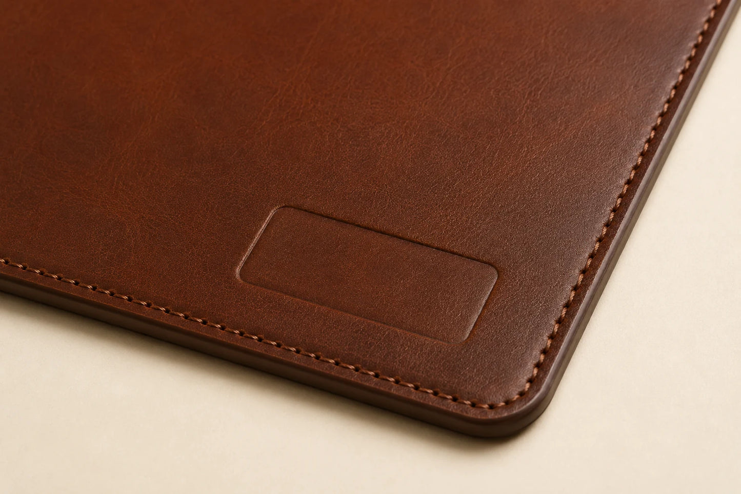 Close-up of leather grain stitching and blank logo area on custom leather desk mat