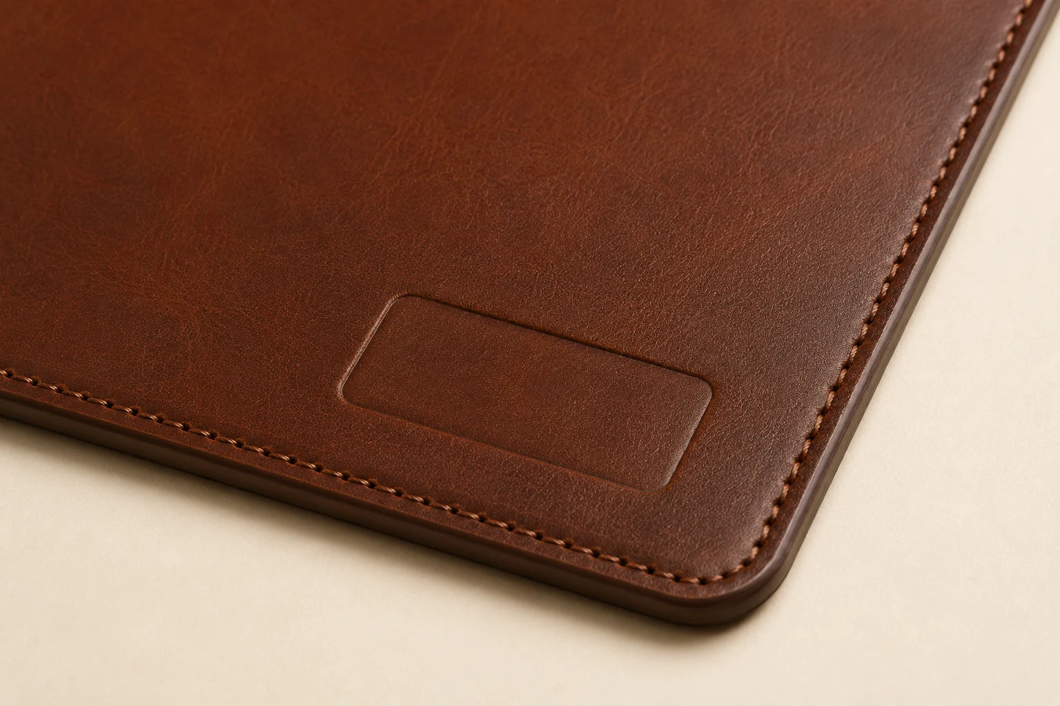Close-up of leather grain stitching and blank logo area on custom leather desk mat