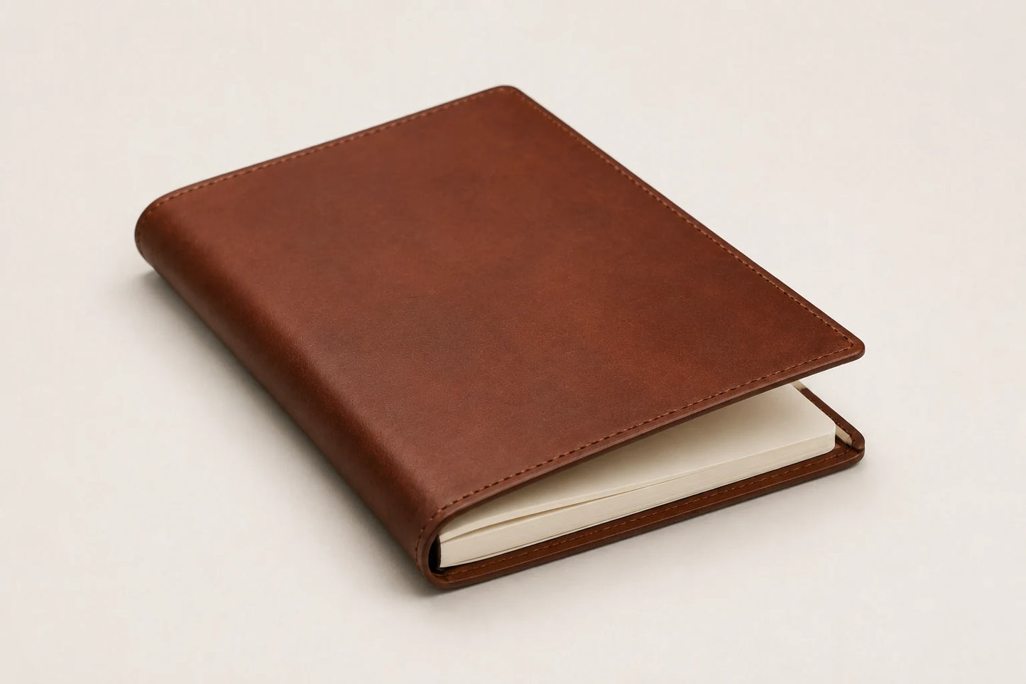Angled view of custom leather journal notebook with blank cream paper insert