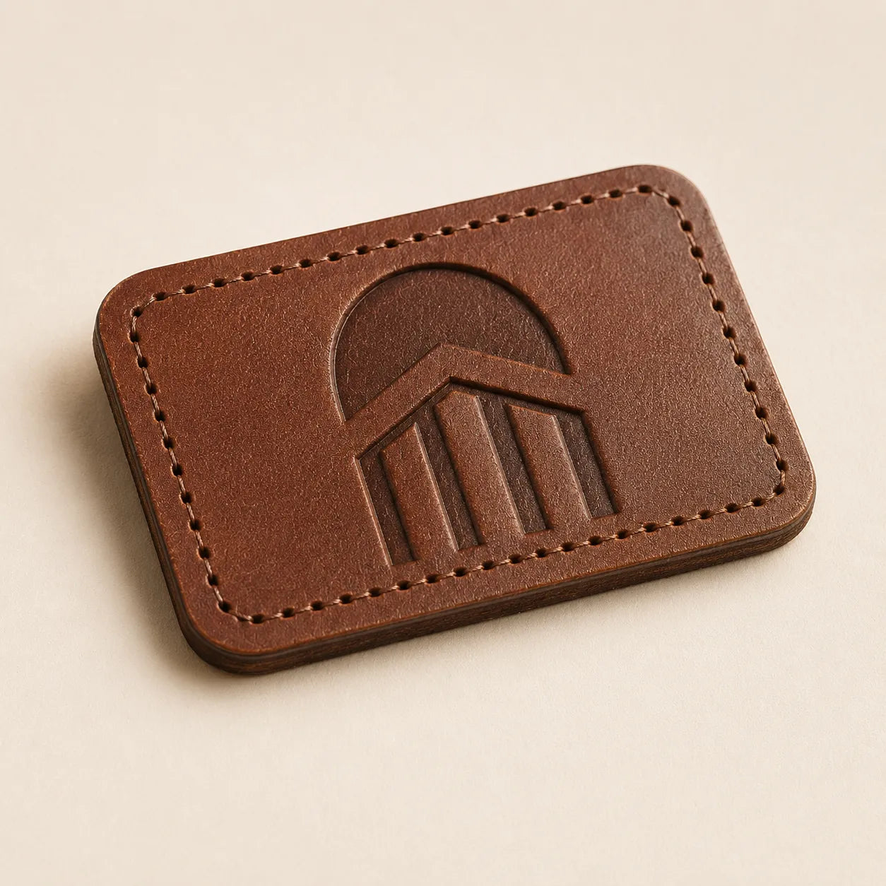 Angled view of custom logo brown leather hat patch with stitch-ready border
