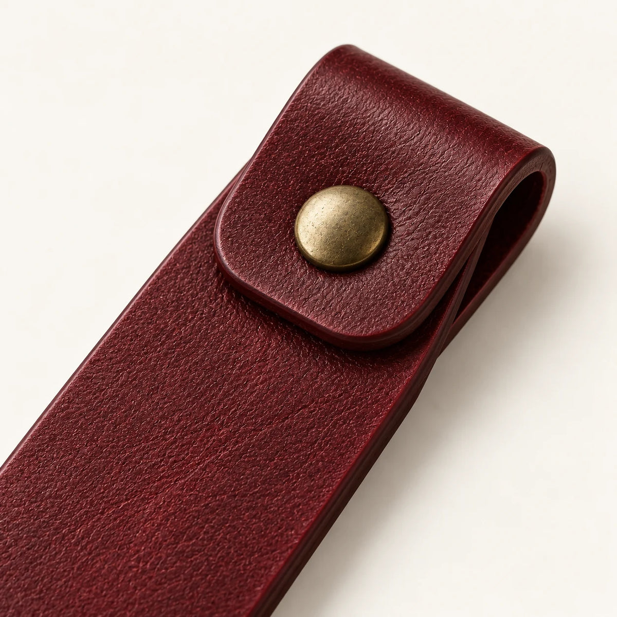 Close-up of the single rivet and folded burgundy leather bookmark tab
