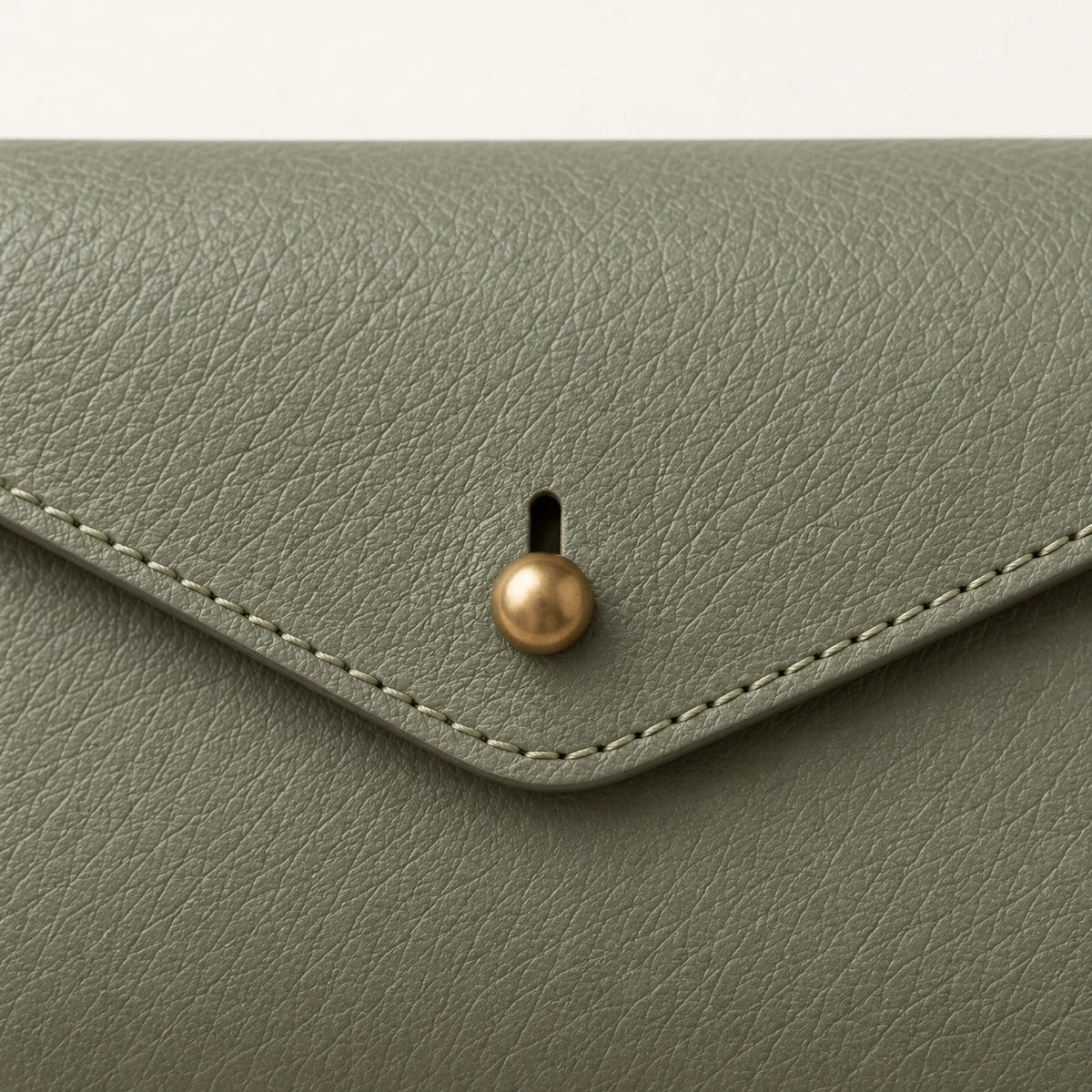 Close-up of the stud-and-slot closure, leather grain and stitching
