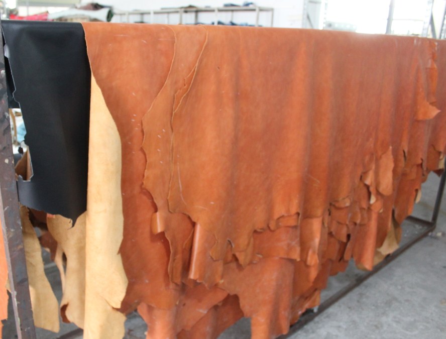 Brown and black leather hides displayed on rails at a Guangzhou leather market