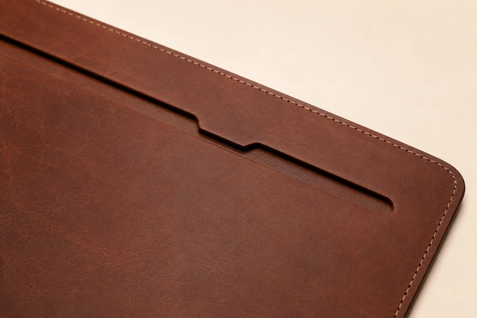 Close-up of cable slot stitched edge and leather grain on brown desk mat