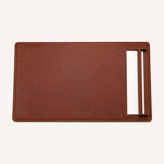 Top-down view of leather desk pad with side paper rail and blank paper sheet