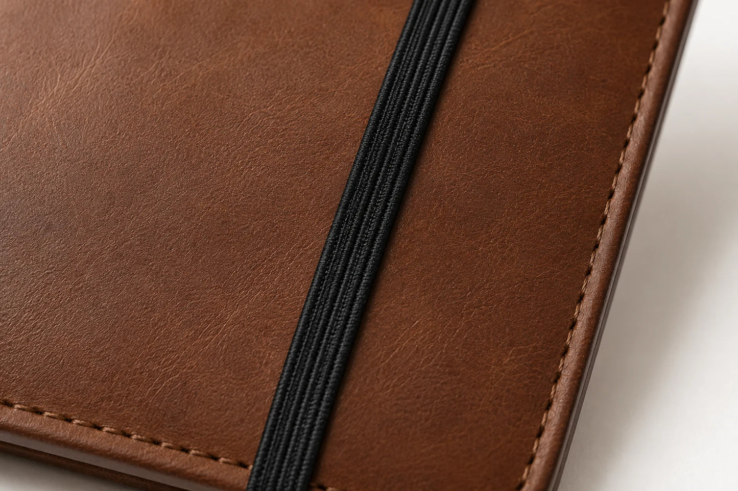 Close-up of black elastic band closure on brown leather journal cover
