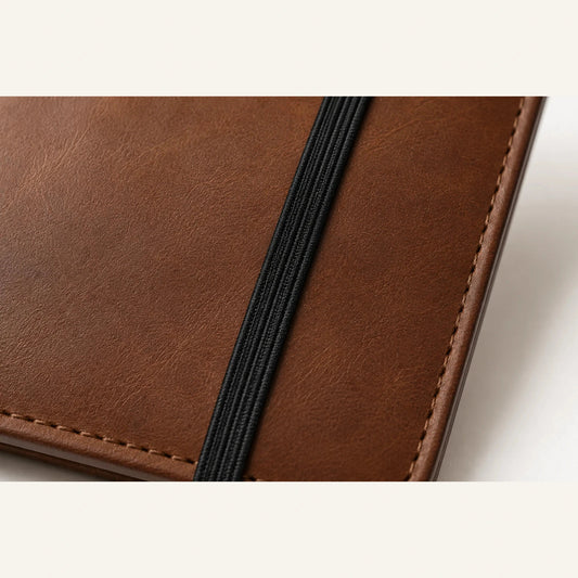 Close-up of black elastic band closure on brown leather journal cover