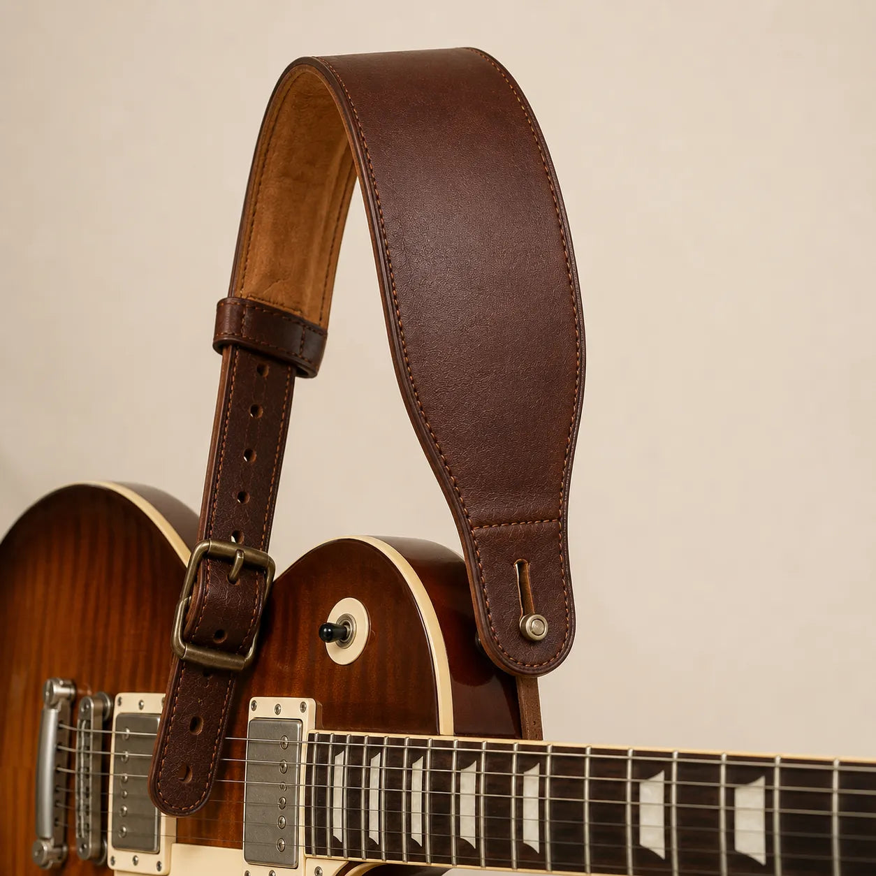 Padded brown leather guitar strap attached to guitar concept sample
