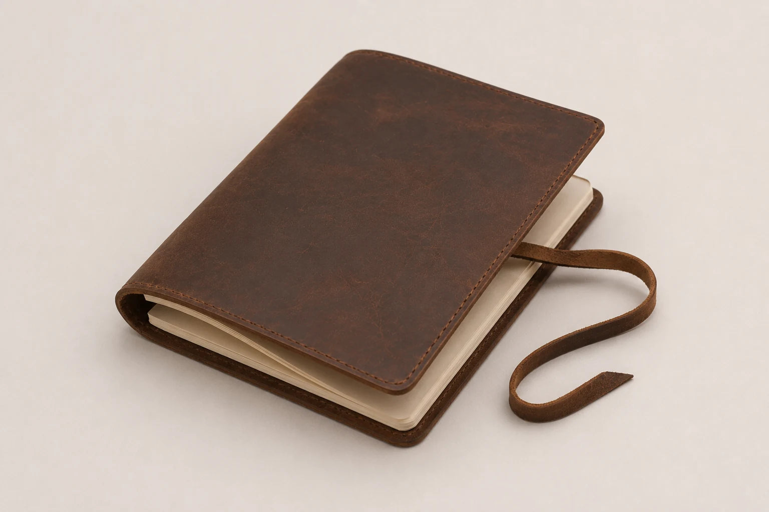 Angled view of leather travel journal with refillable blank paper insert