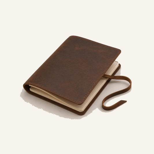 Angled view of leather travel journal with refillable blank paper insert