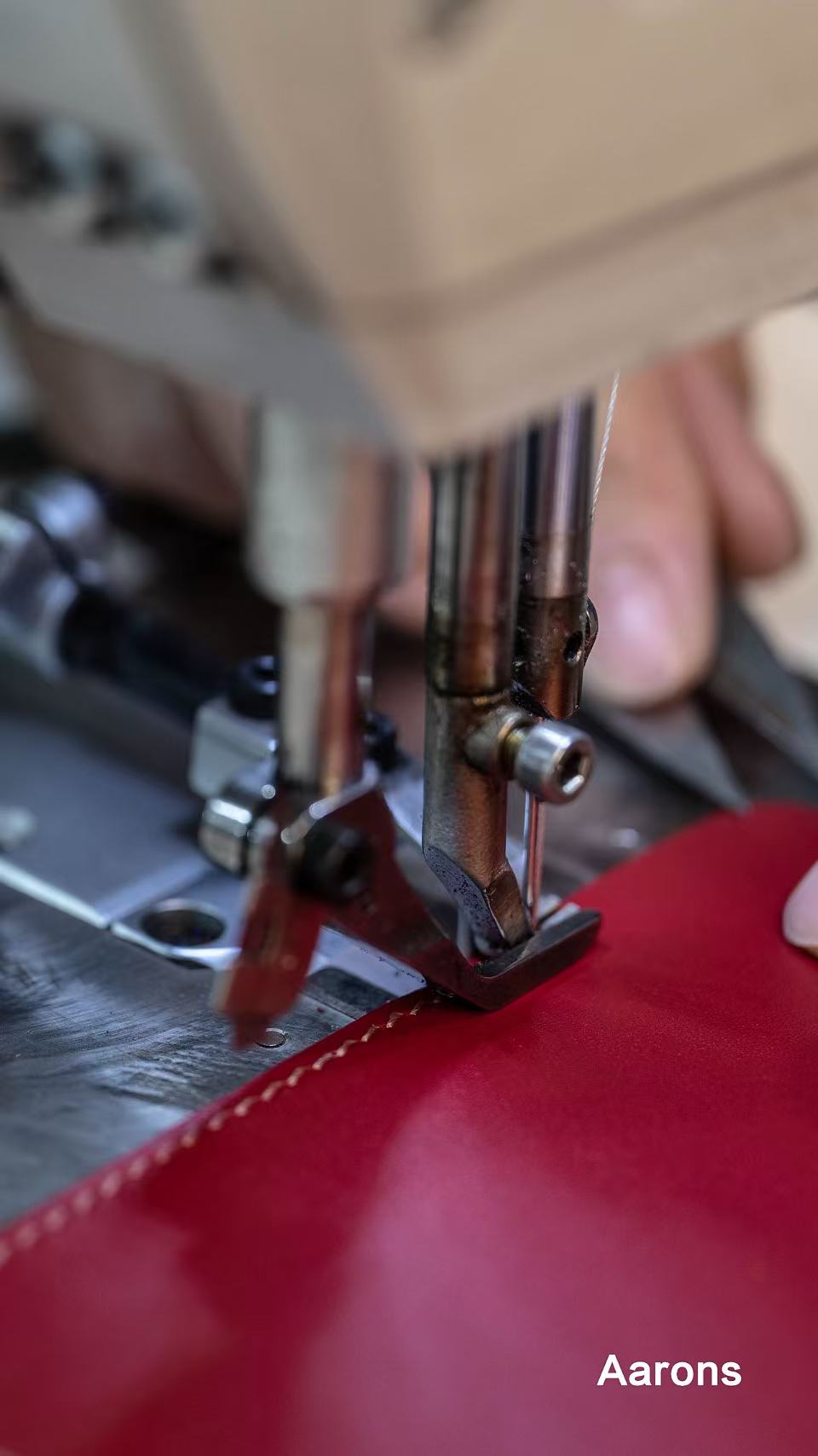 A sewing machine stitching a red leather panel in the Aarons Leather workshop